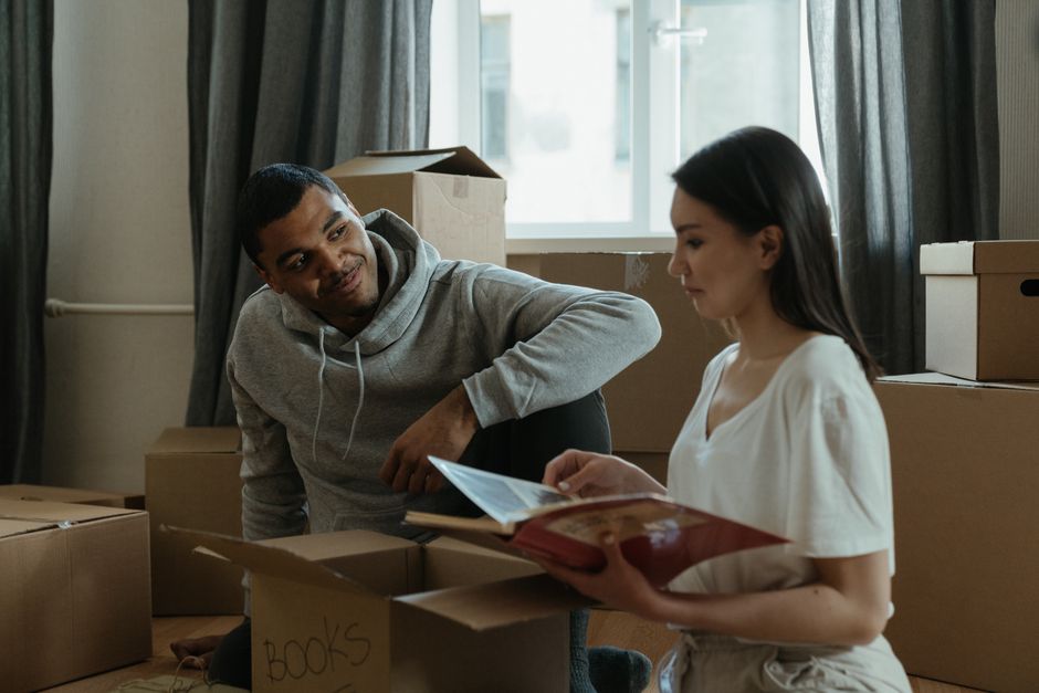 changement d'adresse Annecy – A couple exploring their new home while unpacking boxes and looking at a photo album.